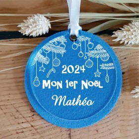 Une décoration fabriquée en Feutrine bleue et personnalisé sur du plexi transparent avec l'année du 1er Noël et le prénom.